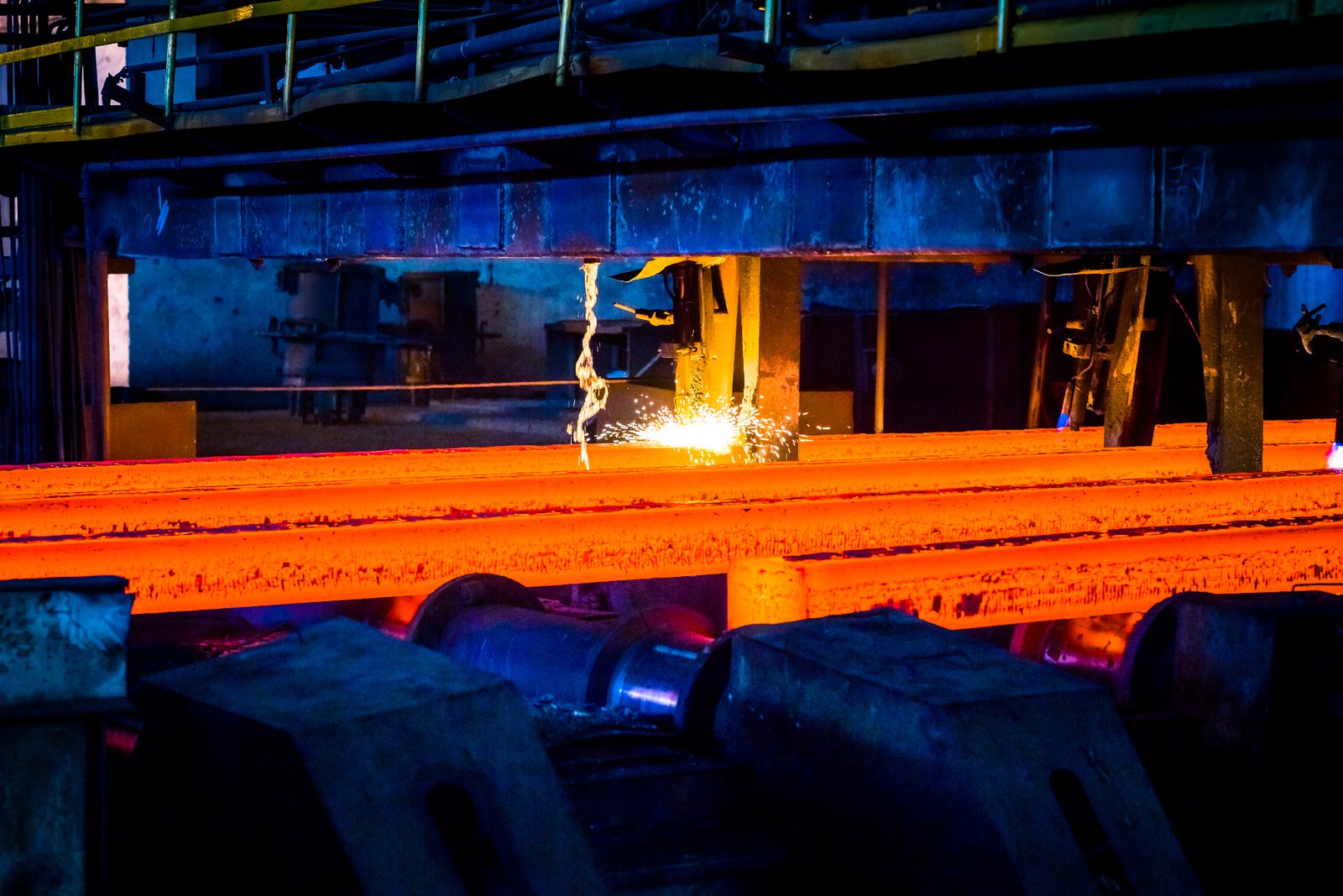 Industrial manufacturing facility with hot glowing metal beams and welding sparks