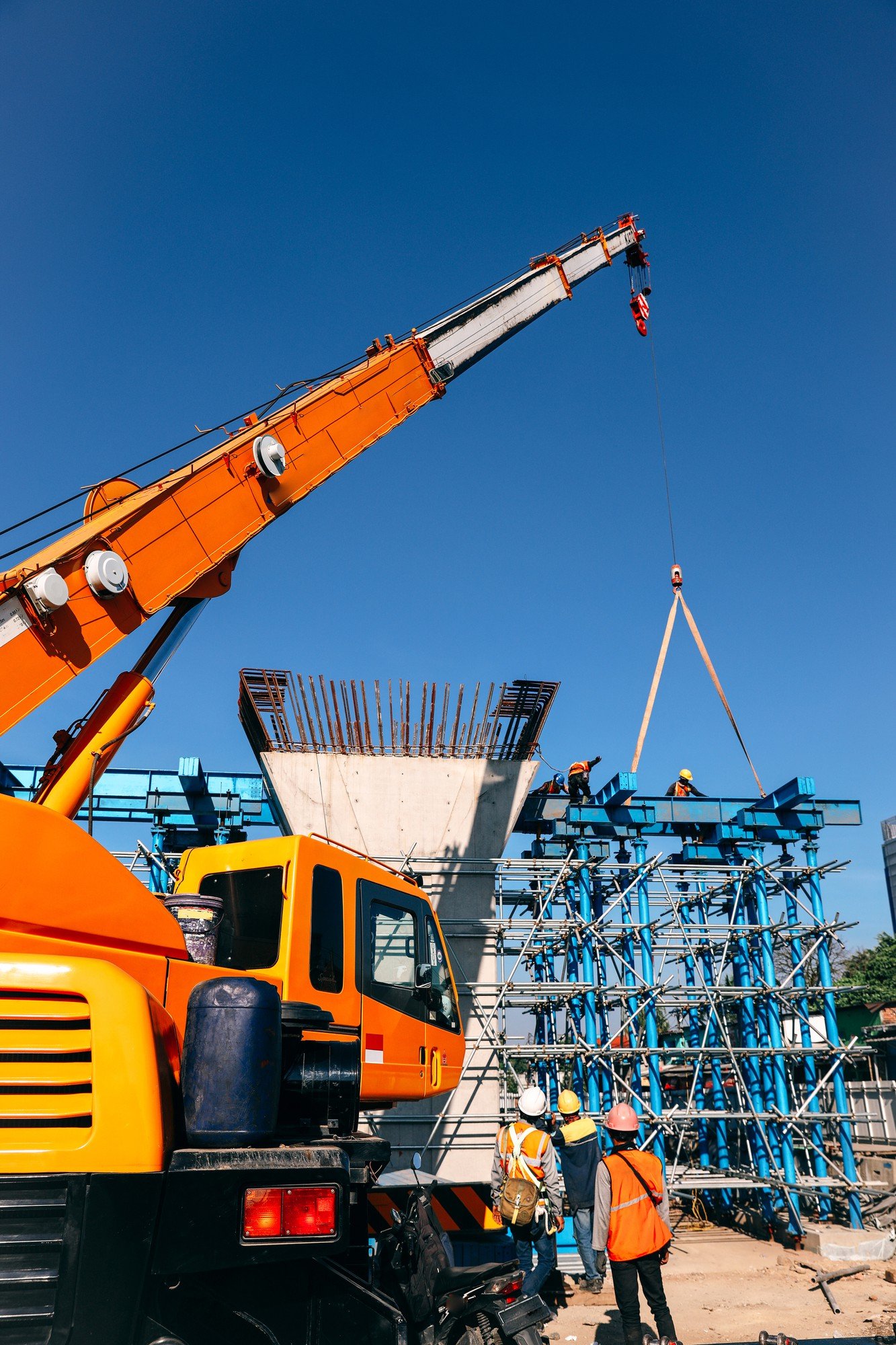 Construction site with crane, workers in safety gear, and scaffolding