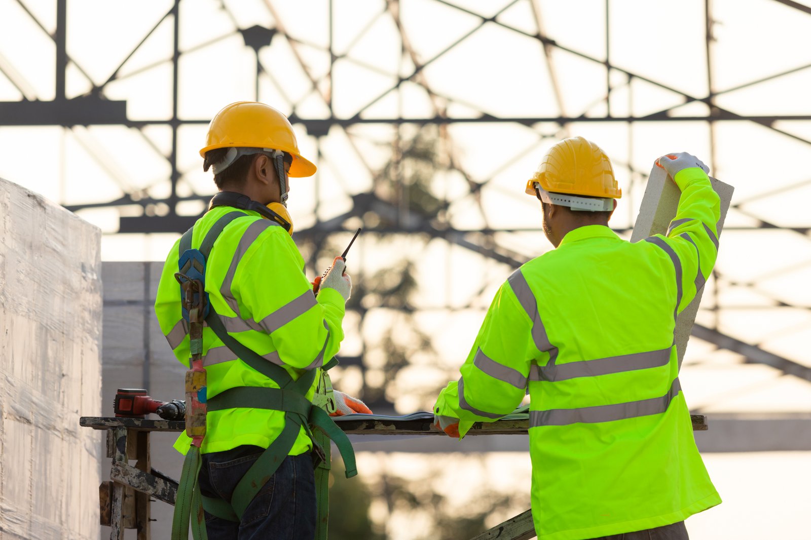 Construction workers in high-visibility gear working on a steel structure