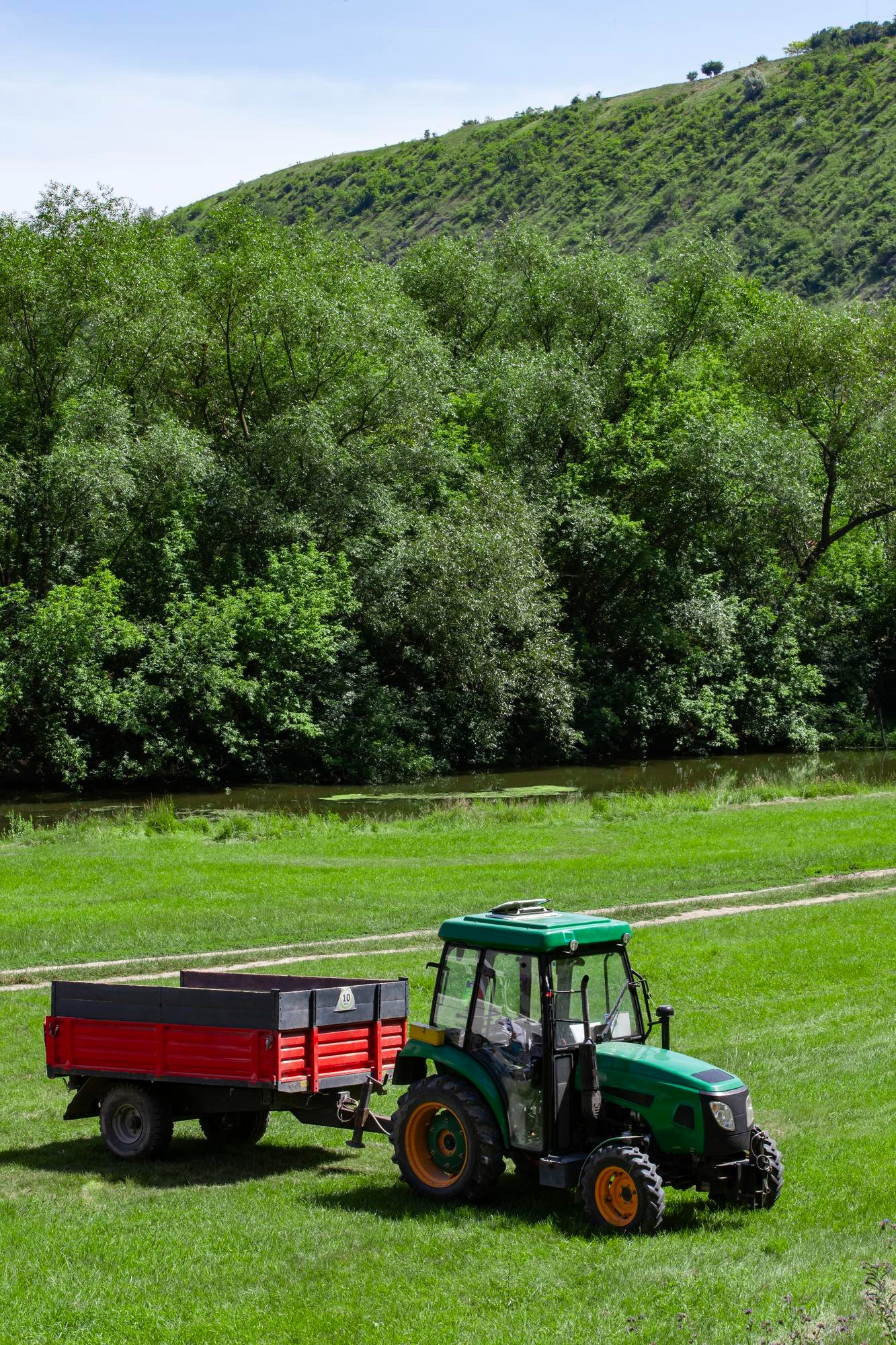 Green tractor with red trailer in a field